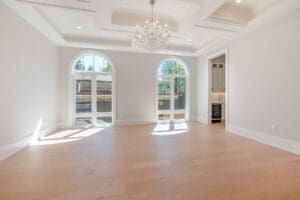 Bright empty room with large arched windows and wooden floor.