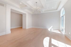 Bright empty room with wooden flooring and chandelier.