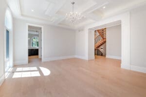 Empty bright room with wooden floors and chandelier lighting.