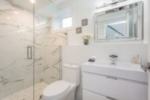 Bright modern bathroom with glass shower and white fixtures.