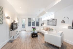 Bright, modern living room with white furniture and wooden floors.