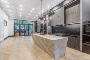 Modern kitchen with marble island and large windows.