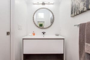 Minimalist bathroom vanity with round mirror and modern faucet.