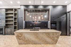 Modern kitchen with a large marble island and hanging Edison bulbs.