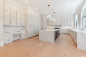 Spacious modern white kitchen with a large island and wooden floors.
