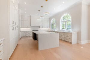 Bright modern kitchen with large white island and arched windows.