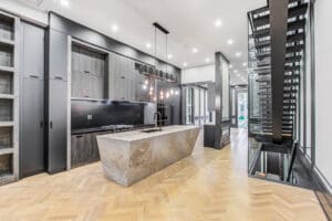 Modern kitchen with marble island and dark cabinetry under bright lighting.