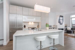 Modern white kitchen with sleek island and bar stools.