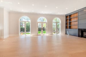 Bright empty room with large arched windows and built-in shelves.