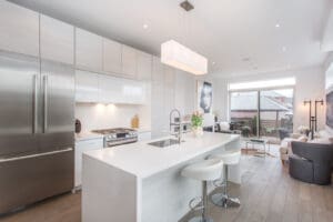 Modern kitchen with white island, stools, and stainless steel appliances.