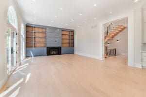 Bright empty living room with built-in shelves and fireplace.