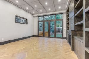 Spacious modern living room with large glass doors and wood flooring.