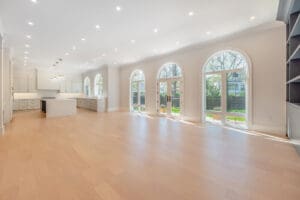 Spacious, bright room with large arched windows and light wood flooring.