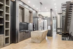 Modern kitchen with large marble island and dark cabinetry.
