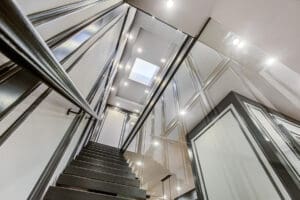 Modern staircase with glass railings and bright lighting.