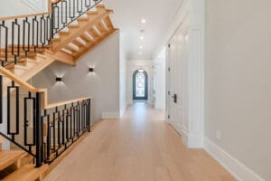 Bright, modern hallway with wooden stairs and elegant lighting.
