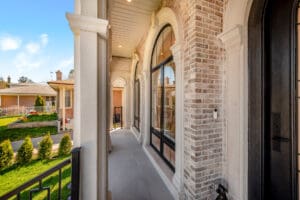 Elegant covered porch with brick walls and arched windows.