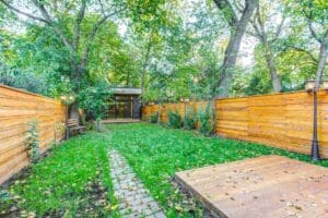 A lush backyard with a wooden fence and stone pathway.