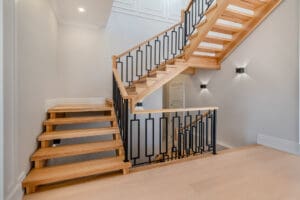 Modern wooden staircase with black metal railing in a bright interior.
