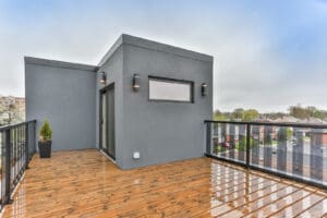 Modern rooftop deck with wooden flooring and gray walls.