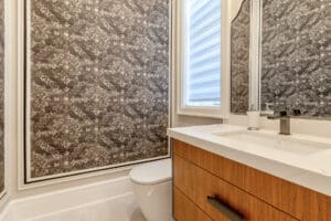 Modern bathroom with patterned wallpaper and wooden vanity.