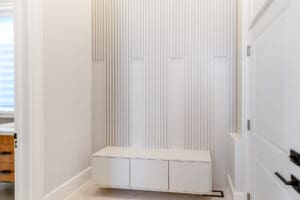 Minimalist white entryway bench with vertical textured wall panels.