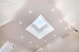 Modern ceiling with a square skylight and recessed lighting.