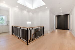 Modern stair railing with black metal and wooden handrail in bright hallway.