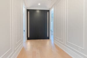 Elegant hallway with black vertical panel accent wall and light wooden flooring.