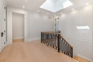 Bright modern hallway with skylights and black railing.
