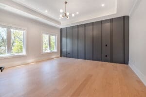 Spacious empty room with large gray closets and wooden flooring.