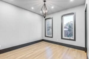 Empty modern room with wooden floor and geometric chandelier.