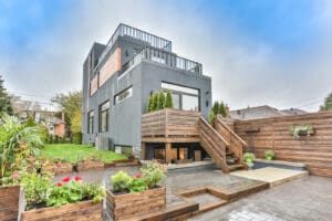 Modern gray house with wooden deck and garden seating area.