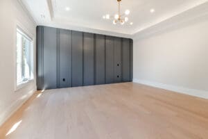 Modern empty room with dark paneled wall and light wooden floor.