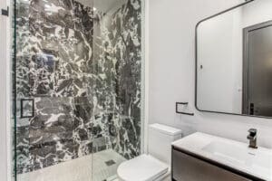 Modern bathroom with marble shower and sleek fixtures.