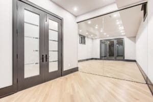 Modern room with large mirrored wall and glass doors.