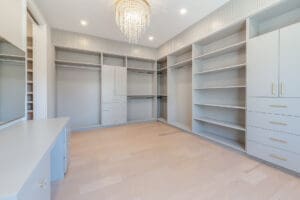 Spacious empty walk-in closet with built-in shelves and a chandelier.