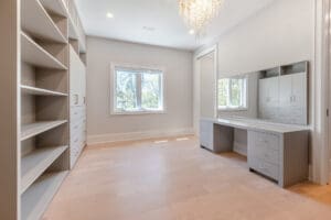 Bright, empty room with built-in shelves and vanity desk under natural light.