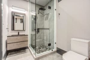 Modern bathroom with glass shower enclosure and wooden vanity.