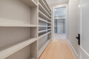 Long hallway with built-in white shelves and light wood flooring.