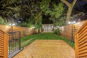 Cozy backyard with wooden deck, grass, and ambient lighting at night.