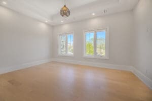Bright empty room with large windows and wooden flooring.