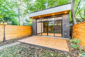 Modern backyard patio with large glass doors and wood fence.