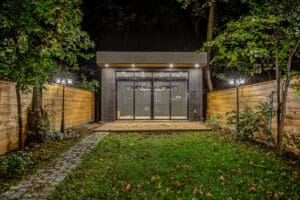 A modern garden room with glass doors lit at night.