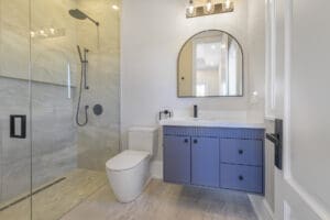 Modern bathroom with blue vanity and large mirror.