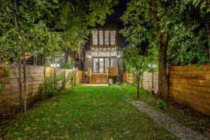 A cozy backyard with a well-lit house at night and a lush green lawn.