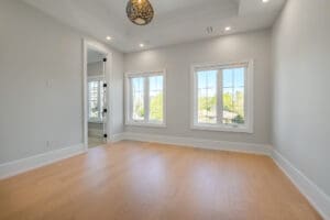 Bright empty room with large windows and light wood flooring.