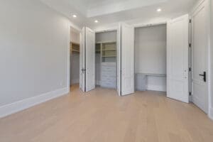 Empty room with open closets and light wood flooring.