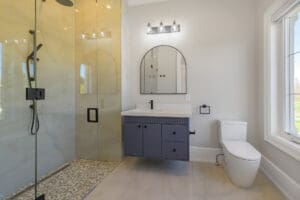 Modern bathroom with glass shower and dark vanity.