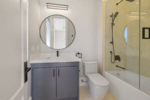 Modern bathroom with a round mirror and glass shower door.